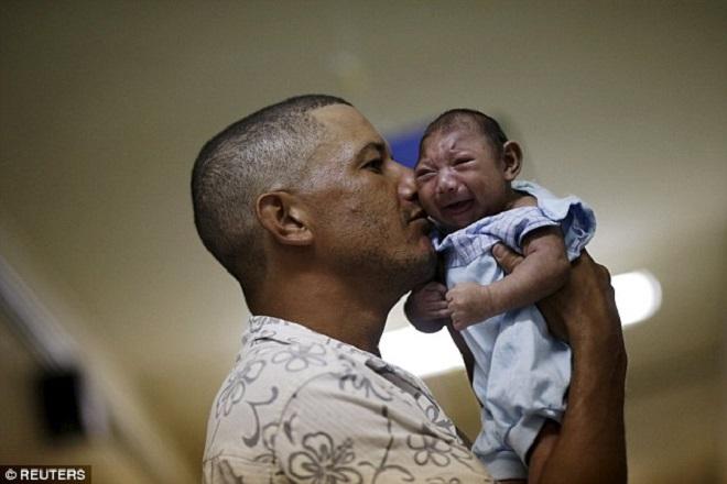 Women of child bearing age are being warned to consider trips to Brazil ’carefully’ ahead of the Olympic Games this August. Pictured: Geovane Silva holds his son Gustavo Henrique, who has microcephaly - one of more than  4,000 babies to be born with the condition in the last 12 months © Reuters