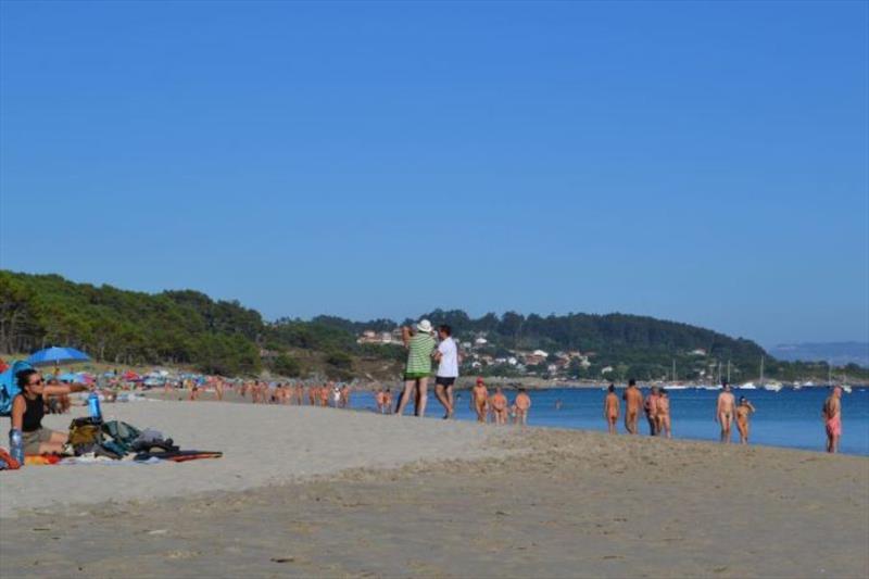 The view from shore, lots of people walking (or parading) along the beach - photo © SV Red Roo