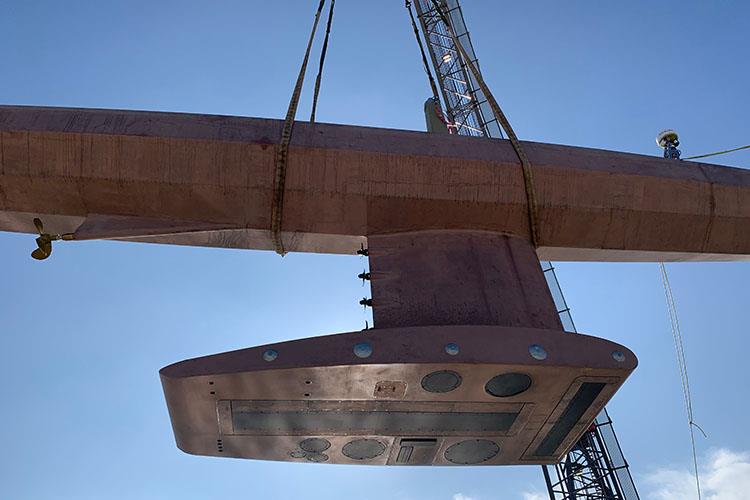 The hull of Saildrone Surveyor being lifted into water by crane. Surveyor is equipped with a sophisticated array of acoustic instruments including the Kongsberg EM304 multibeam sonar, Simrad EK80 echo sounder, Teledyne Pinnacle ADCP, and Simrad EC150 ADCP - photo © Saildrone