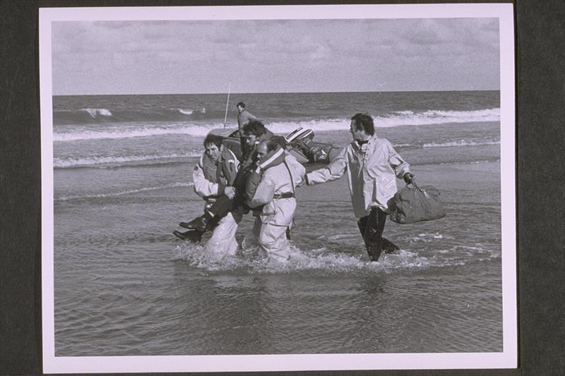 Cromer. D class Lifeboat on beach. Two lifeboat crewmen carrying a man with another supporting him from behind. Crew left to right Ted Luckin (helmsman), Eric Love and Chris Craske - photo © RNLI
